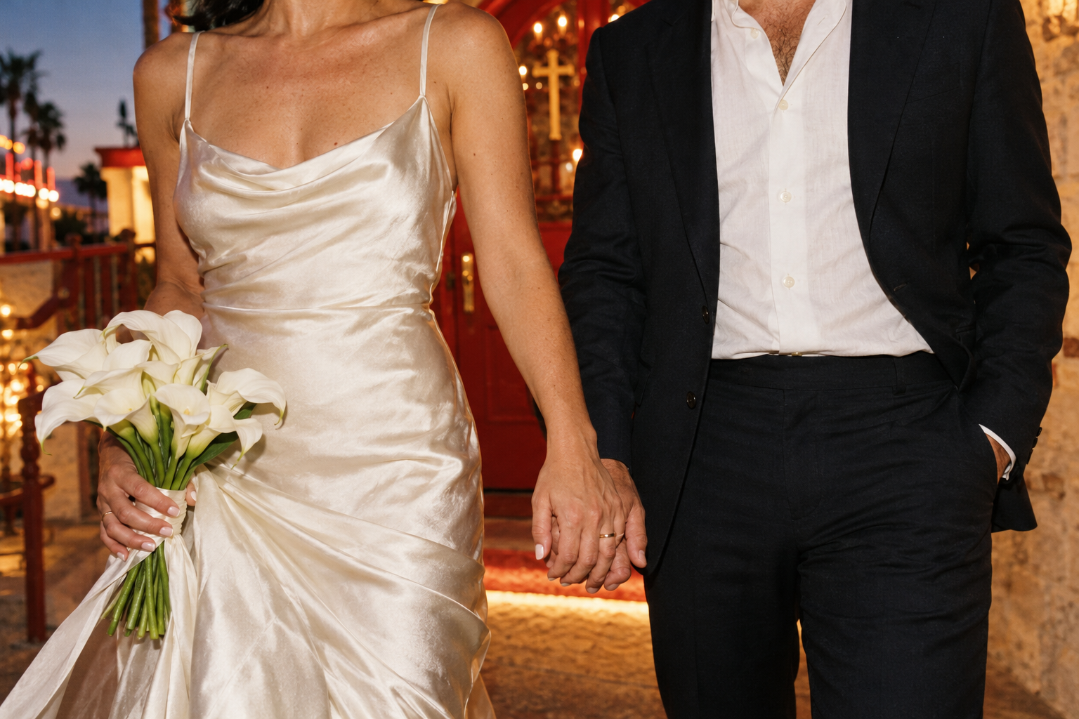 Two newlyweds holding hands, with a white calla lily bouquet and an ivory wedding dress